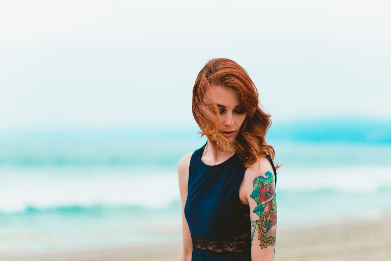 jeune femme sur une plage avec un tatouage coloré sur le bras